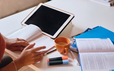 girl-studying-with-tablet-textbooks-and-cup-of-coffee-on-desk-at-cozy-home