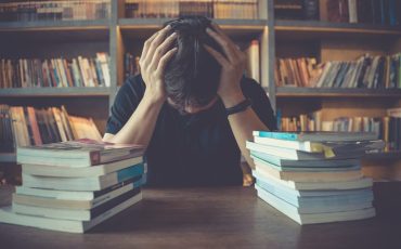 stress-and-tired-man-under-mental-pressure-while-reading-book-preparing-examination-in-library-1200x800